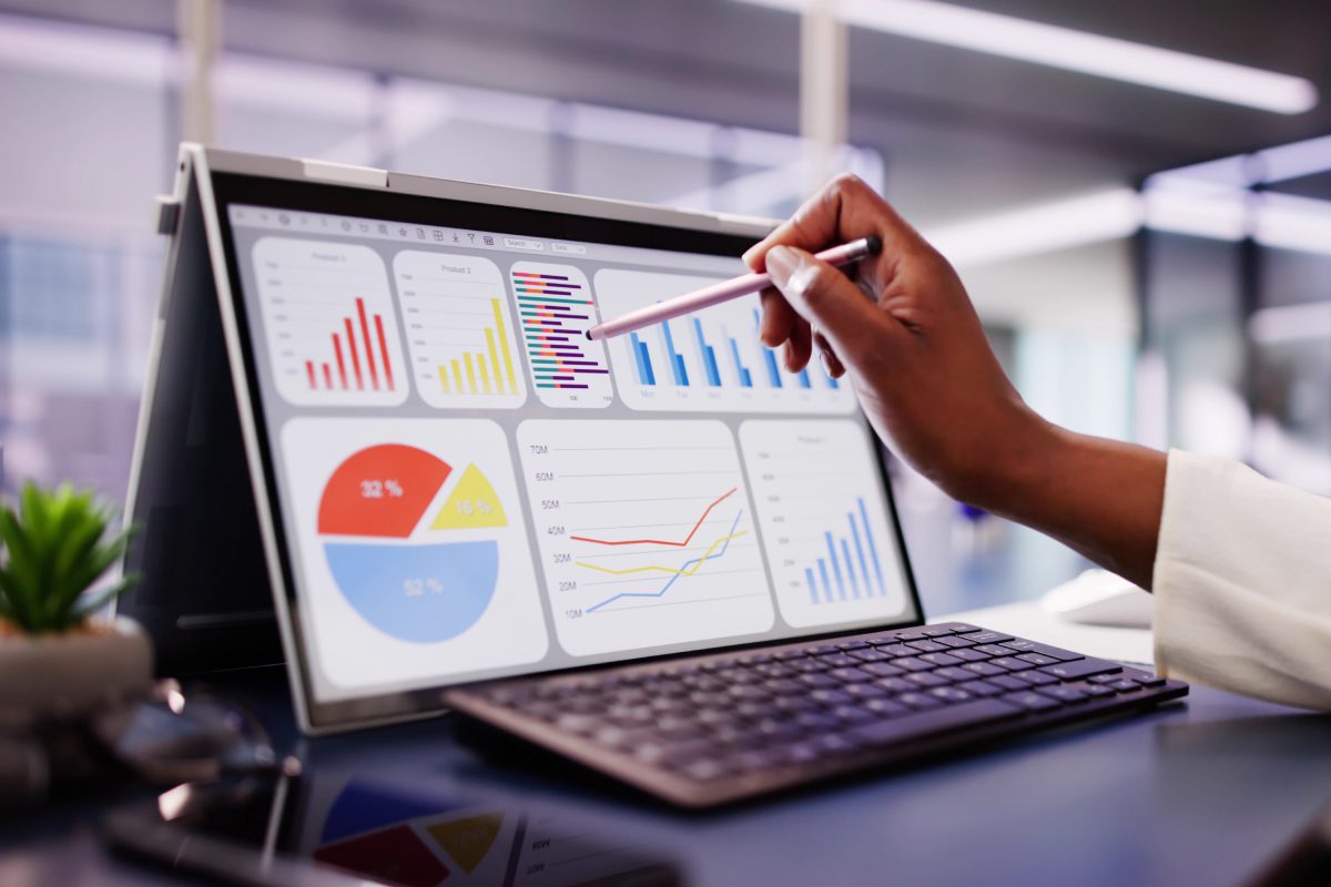 Person analyzing colorful business charts on a tablet in an office.