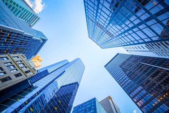 Looking up at towering modern skyscrapers against a clear blue sky.
