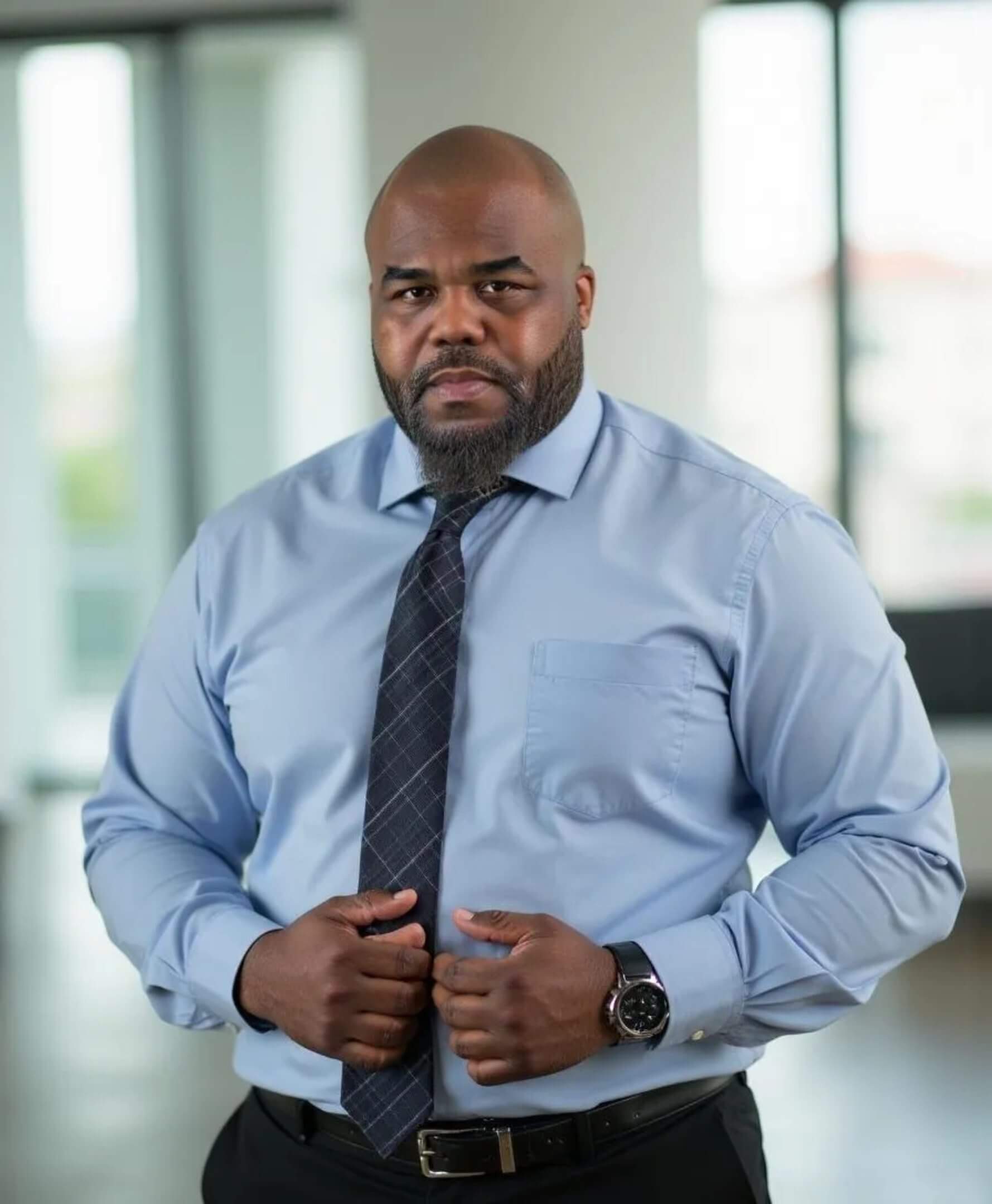 Man in blue shirt, standing confidently indoors.
