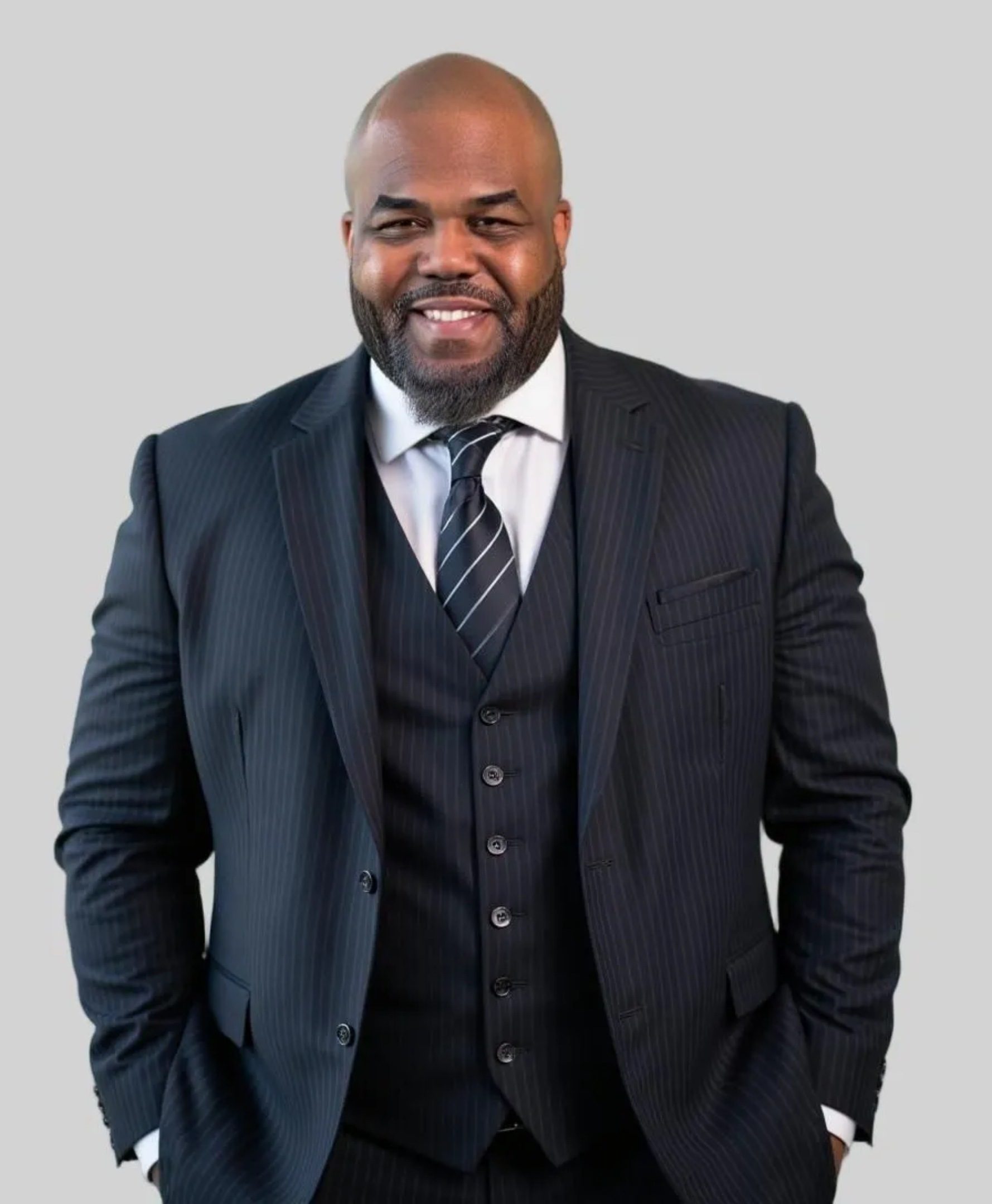 Man in a dark suit smiling confidently.