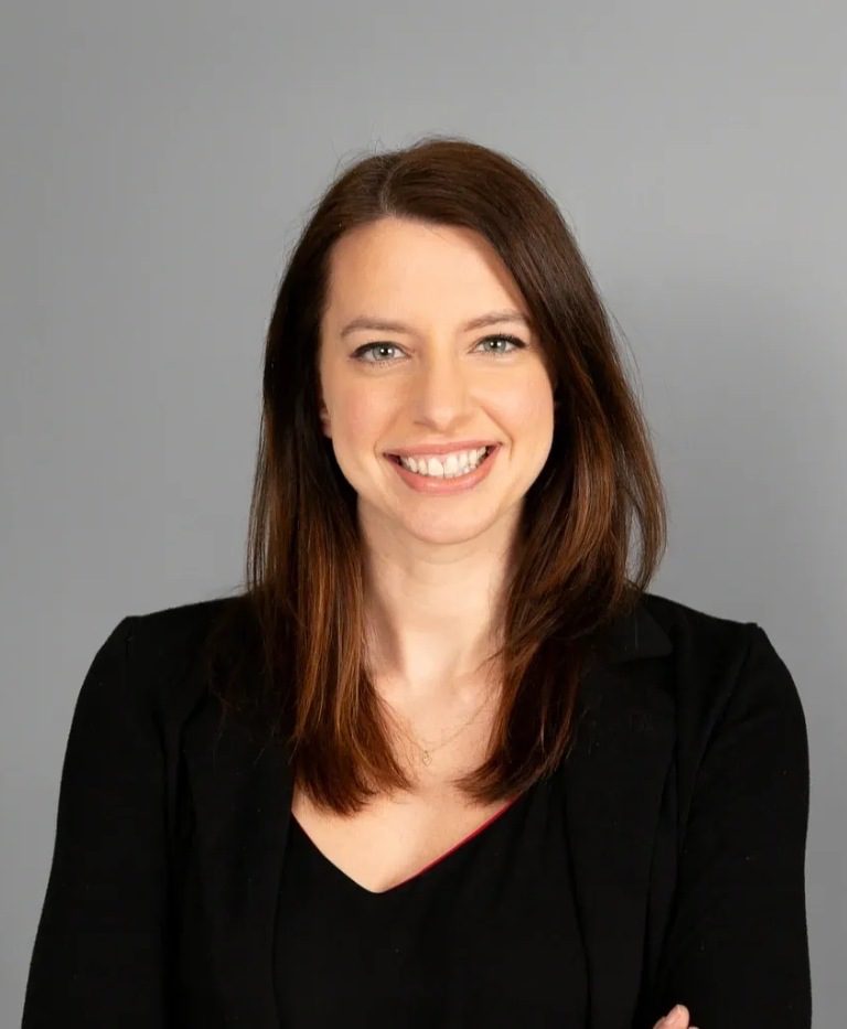 Smiling woman with brown hair, black jacket.