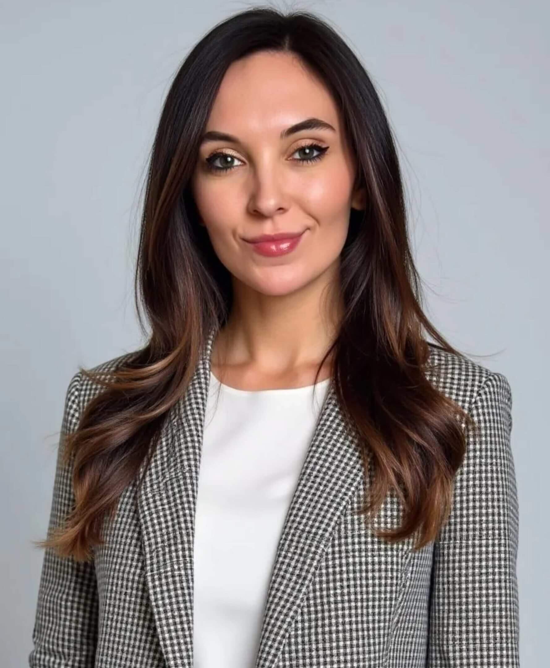 Woman in a checkered blazer smiling confidently.