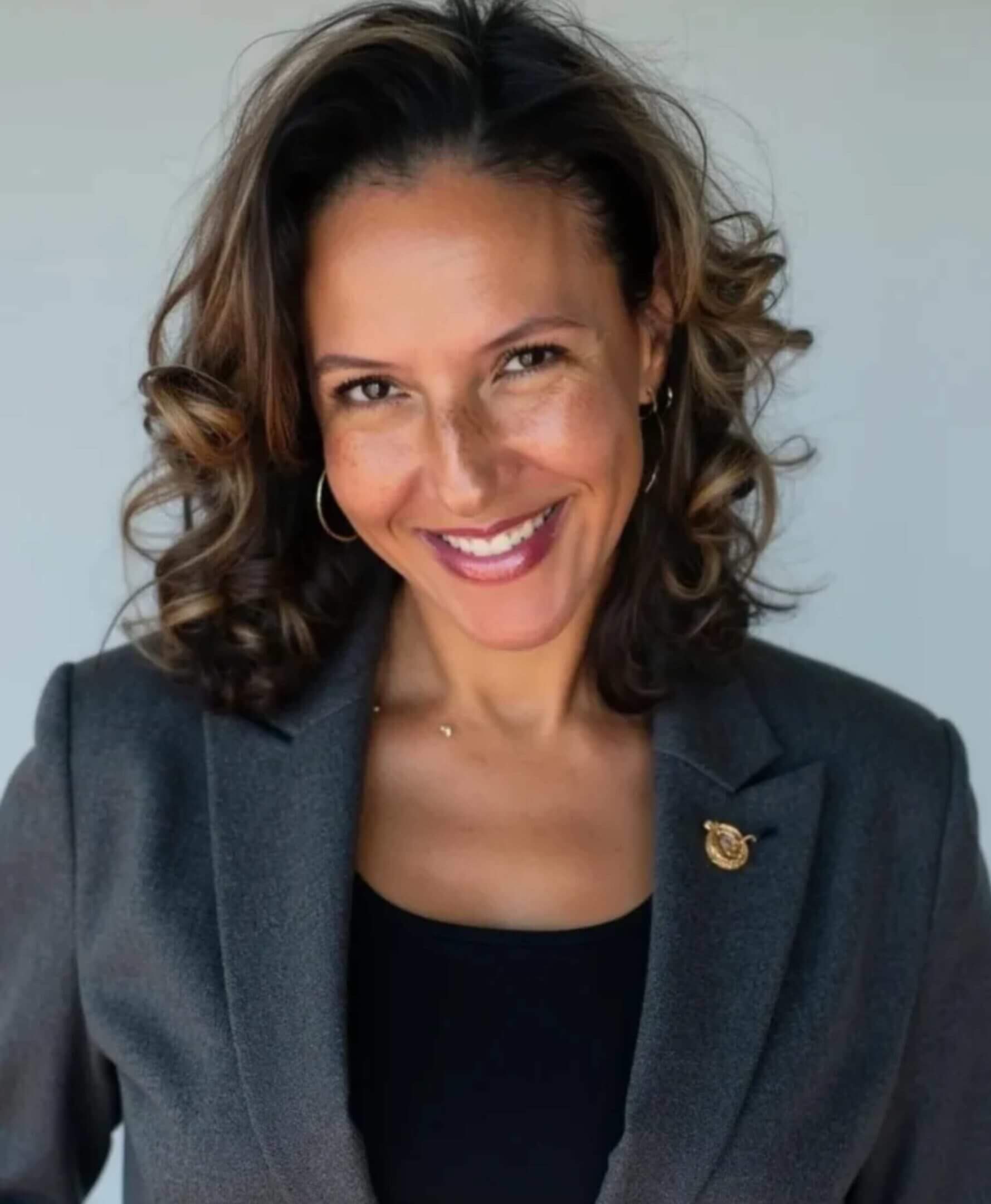 Smiling businesswoman headshot in gray blazer