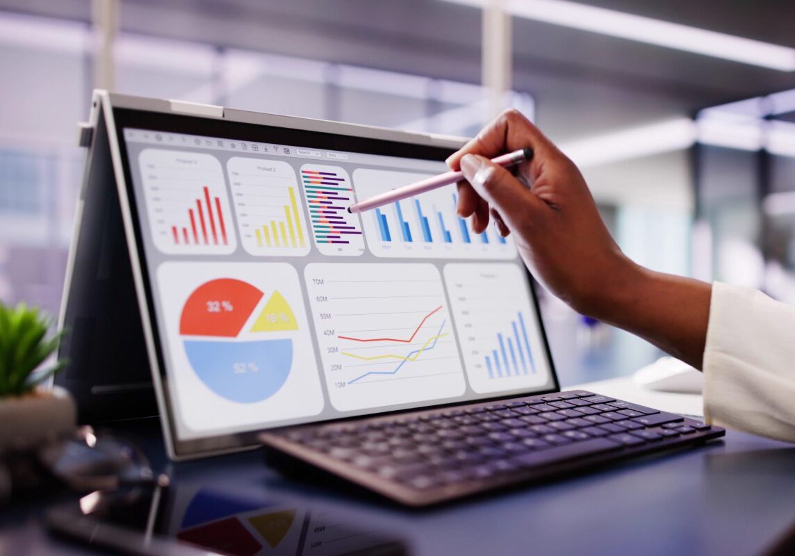 Person analyzing colorful business charts on a tablet in an office.