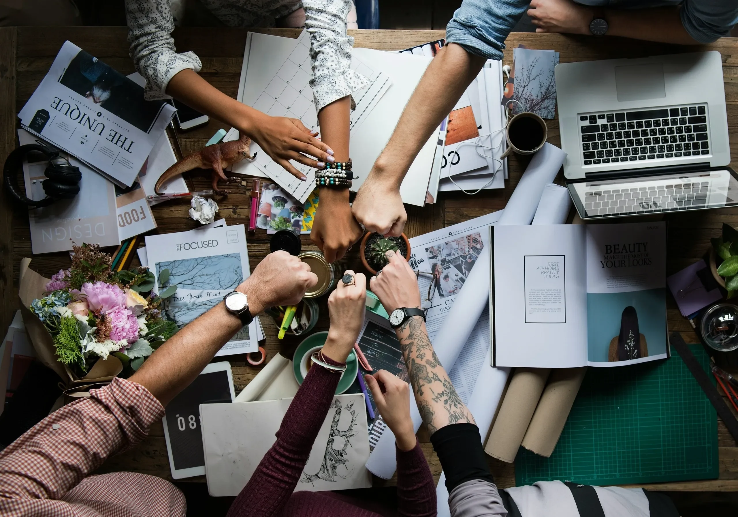 Creative team fist bump over cluttered workspace